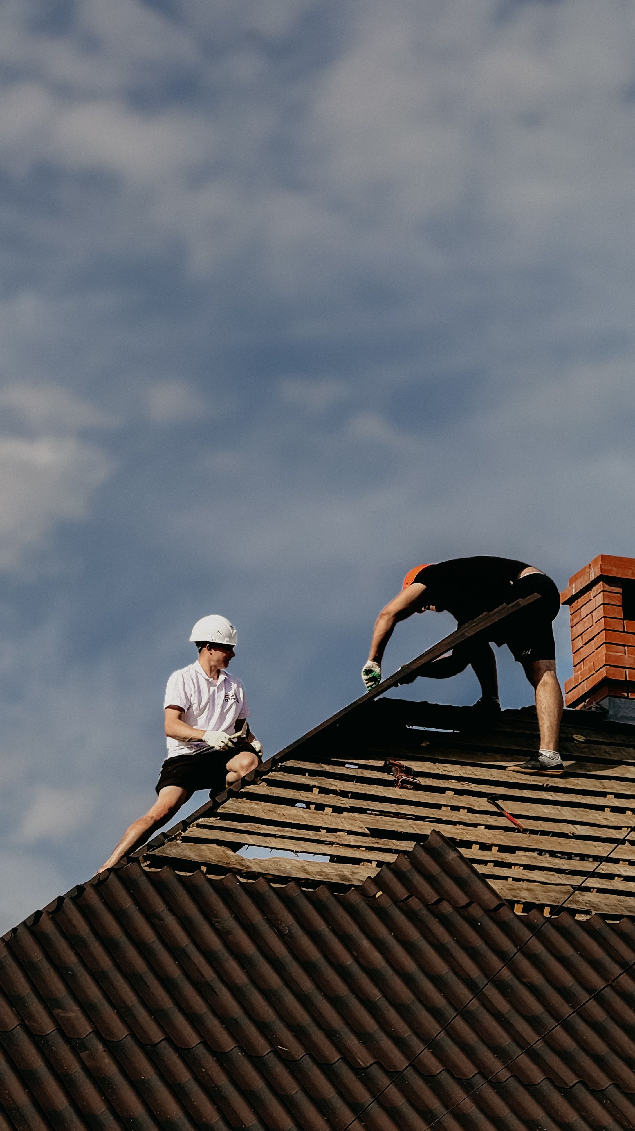Roofing crew working on a roof against a dramatic sky